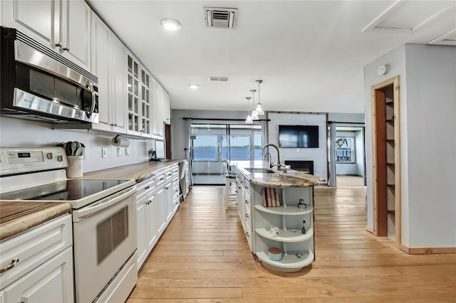 550 George St S, Tarpon Springs, FL 34688 - kitchen featuring stainless steel microwave, electric range, open shelves, white cabinets, and light wood-style flooring