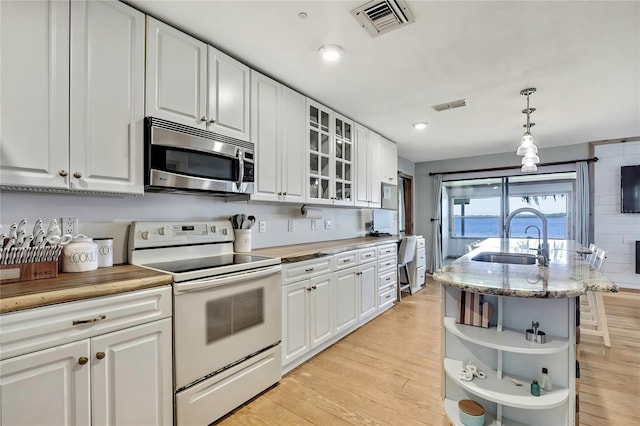 550 George St S, Tarpon Springs, FL 34688 - kitchen with white range with electric cooktop, stainless steel microwave, a sink, open shelves, and light wood-style floors