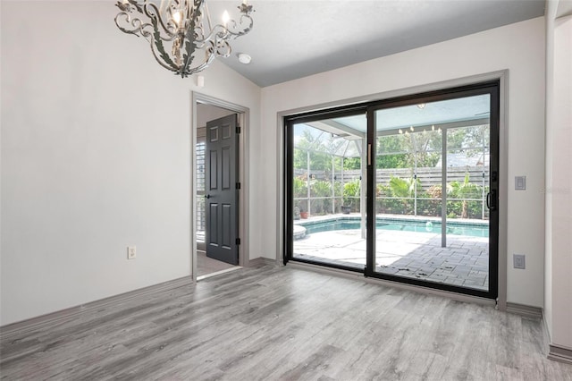 2320 James Ln, Sarasota, FL 34231 - unfurnished room featuring wood finished floors, a chandelier, and vaulted ceiling