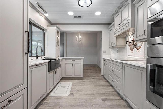 2320 James Ln, Sarasota, FL 34231 - kitchen featuring oven, gray cabinetry, a chandelier, light wood finished floors, and crown molding