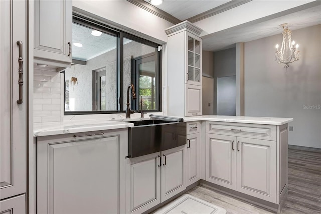 2320 James Ln, Sarasota, FL 34231 - kitchen with crown molding, light wood-style floors, a peninsula, glass insert cabinets, and a chandelier