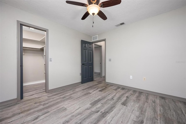 2320 James Ln, Sarasota, FL 34231 - unfurnished bedroom featuring wood finished floors, a spacious closet, a textured ceiling, and ceiling fan