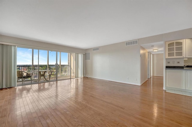 10355 Paradise Blvd Unit 502, Treasure Island, FL 33706 - unfurnished living room with light wood finished floors and baseboards