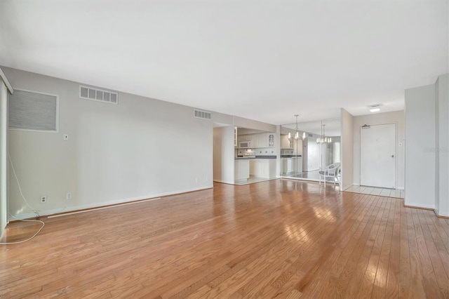 10355 Paradise Blvd Unit 502, Treasure Island, FL 33706 - unfurnished living room with a chandelier, light wood-style flooring, and baseboards