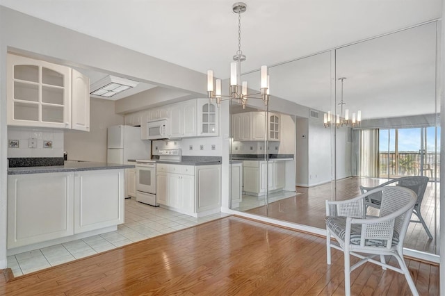 10355 Paradise Blvd Unit 502, Treasure Island, FL 33706 - kitchen featuring white appliances, a chandelier, dark countertops, glass insert cabinets, and light wood-style flooring
