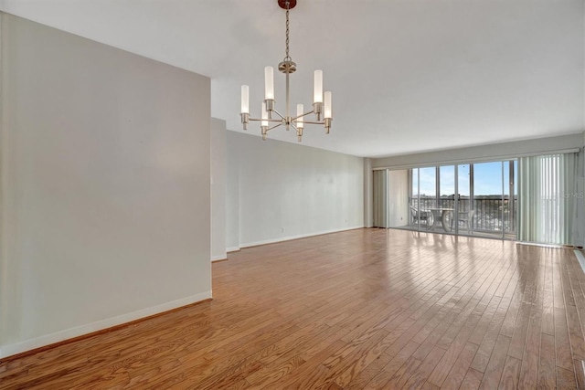 10355 Paradise Blvd Unit 502, Treasure Island, FL 33706 - unfurnished room with a chandelier, wood finished floors, and baseboards