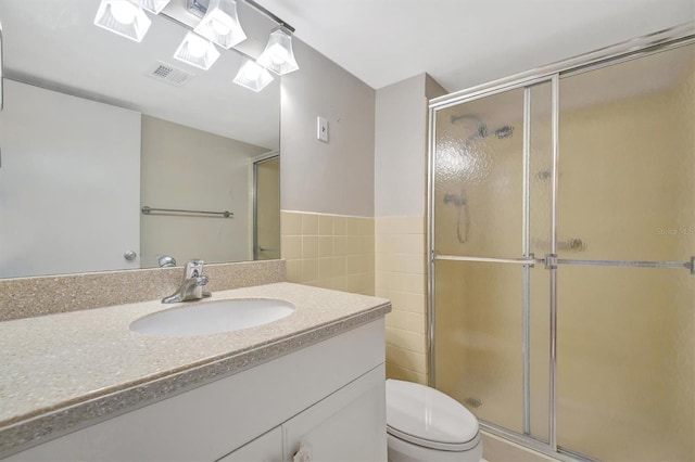 10355 Paradise Blvd Unit 502, Treasure Island, FL 33706 - bathroom with tile walls, a stall shower, toilet, vanity, and a wainscoted wall