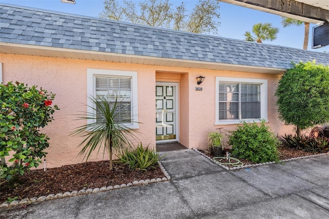 3839 Trophy Blvd Unit 3839, New Port Richey, FL 34655 - view of exterior entry featuring roof with shingles, stucco siding, and mansard roof