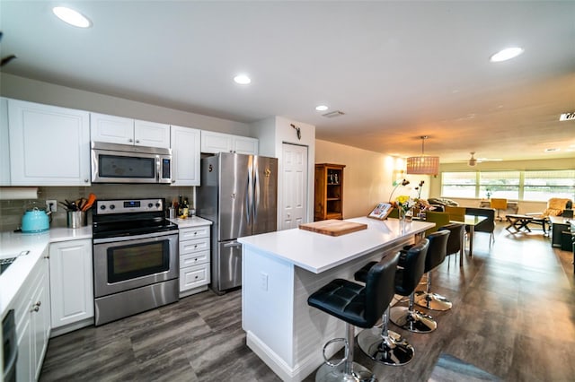 3850 13th Ave N Unit 113, Saint Petersburg, FL 33713 - kitchen with appliances with stainless steel finishes, white cabinets, a breakfast bar, light countertops, and recessed lighting
