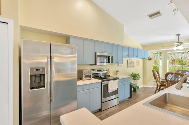 11148 Hollander Ave, Hudson, FL 34667 - kitchen featuring appliances with stainless steel finishes, blue cabinetry, a sink, vaulted ceiling, and light wood-type flooring