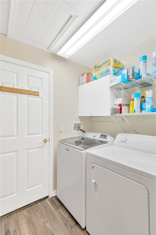 11148 Hollander Ave, Hudson, FL 34667 - clothes washing area with washing machine and dryer, cabinet space, and light wood-type flooring