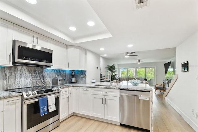 9812 Indian Key Trl Unit 84, Seminole, FL 33776 - kitchen featuring stainless steel appliances, a peninsula, a sink, open floor plan, and light wood-style flooring