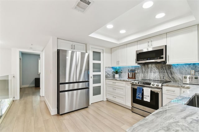 9812 Indian Key Trl Unit 84, Seminole, FL 33776 - kitchen featuring appliances with stainless steel finishes, a raised ceiling, white cabinets, light wood-type flooring, and recessed lighting