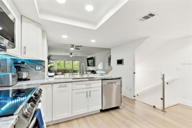9812 Indian Key Trl Unit 84, Seminole, FL 33776 - kitchen with appliances with stainless steel finishes, a sink, a peninsula, recessed lighting, and light wood-type flooring