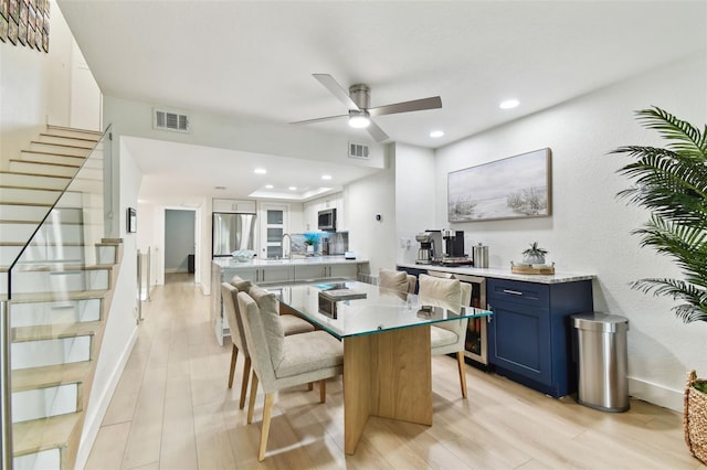 9812 Indian Key Trl Unit 84, Seminole, FL 33776 - kitchen featuring blue cabinetry, appliances with stainless steel finishes, a ceiling fan, a kitchen breakfast bar, and light wood-type flooring