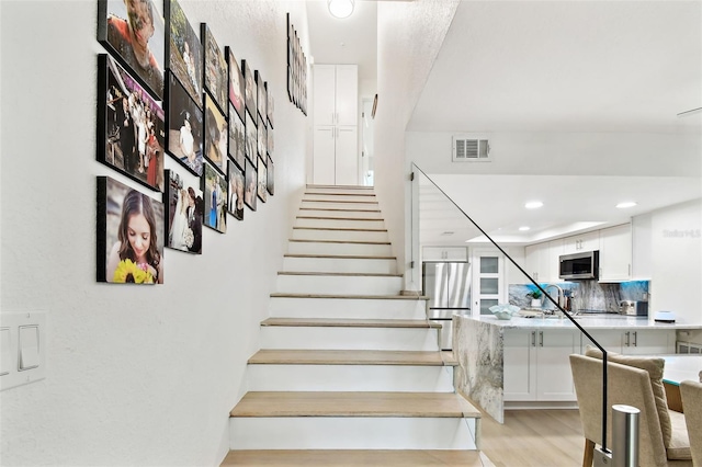 9812 Indian Key Trl Unit 84, Seminole, FL 33776 - staircase featuring wood finished floors and recessed lighting