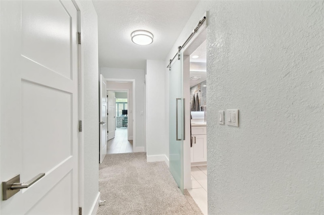 9812 Indian Key Trl Unit 84, Seminole, FL 33776 - hallway featuring a barn door, light colored carpet, a textured wall, baseboards, and a textured ceiling