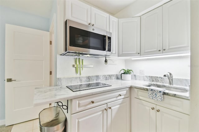 9812 Indian Key Trl Unit 84, Seminole, FL 33776 - kitchen with stainless steel microwave, black electric cooktop, light countertops, and white cabinets