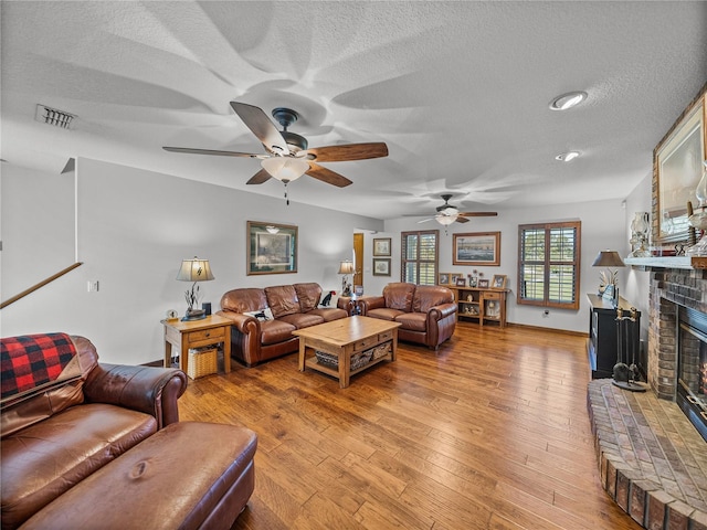 16326 Kalli Way, Dade City, FL 33523 - living area featuring a textured ceiling, a fireplace, ceiling fan, and light wood-style floors