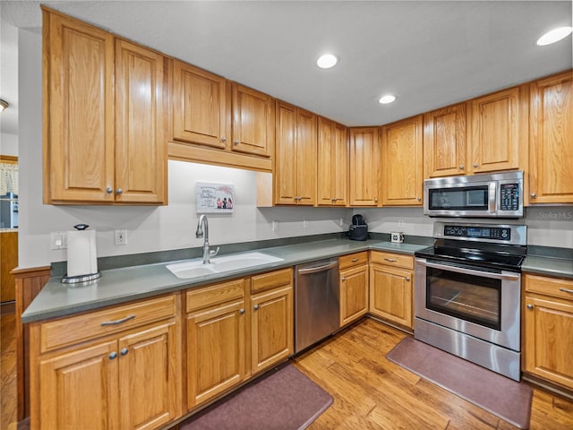 16326 Kalli Way, Dade City, FL 33523 - kitchen with appliances with stainless steel finishes, a sink, light wood-style floors, recessed lighting, and dark countertops