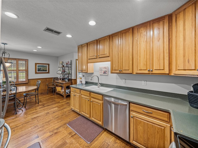 16326 Kalli Way, Dade City, FL 33523 - kitchen featuring dishwasher, a sink, a textured ceiling, light wood-style flooring, and a wainscoted wall