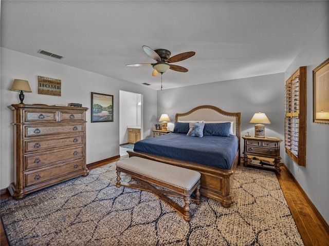 16326 Kalli Way, Dade City, FL 33523 - bedroom with wood finished floors, baseboards, ceiling fan, ensuite bath, and a textured ceiling