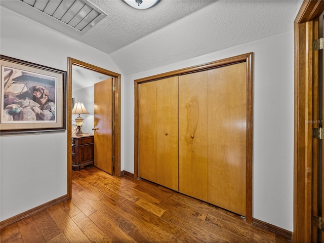 16326 Kalli Way, Dade City, FL 33523 - unfurnished bedroom featuring vaulted ceiling, baseboards, wood-type flooring, a textured ceiling, and a closet