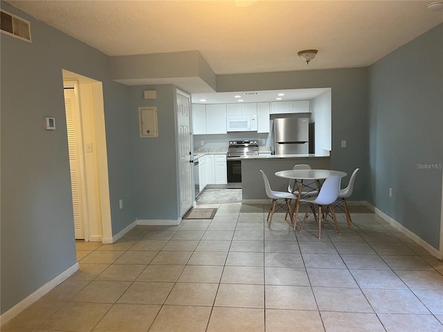 4008 Ashford Green Pl Unit F101, Tampa, FL 33613 - kitchen with stainless steel electric stove, fridge, white microwave, a peninsula, and white cabinets