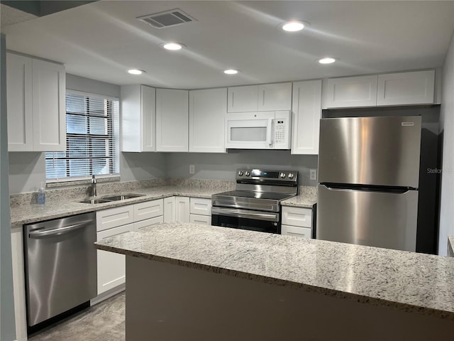 4008 Ashford Green Pl Unit F101, Tampa, FL 33613 - kitchen featuring stainless steel appliances, a sink, white cabinetry, light stone counters, and recessed lighting