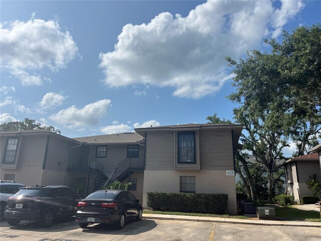 4008 Ashford Green Pl Unit F101, Tampa, FL 33613 - view of property featuring uncovered parking, stucco siding, stairs, and cooling unit