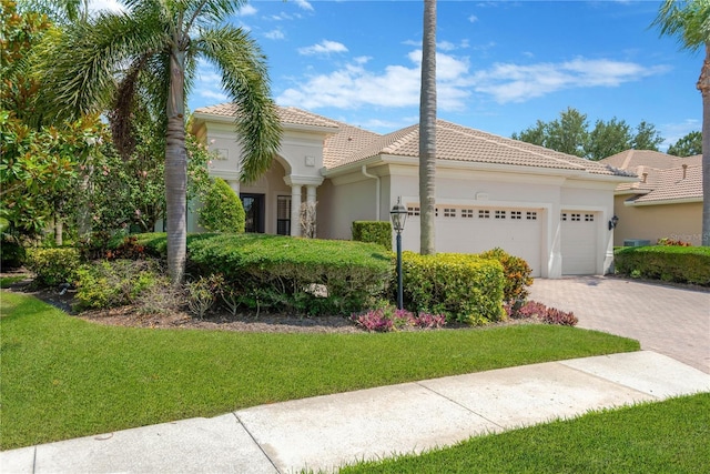 13872 Siena Loop, Lakewood Ranch, FL 34202 - mediterranean / spanish home featuring a garage, a tiled roof, decorative driveway, stucco siding, and a front lawn