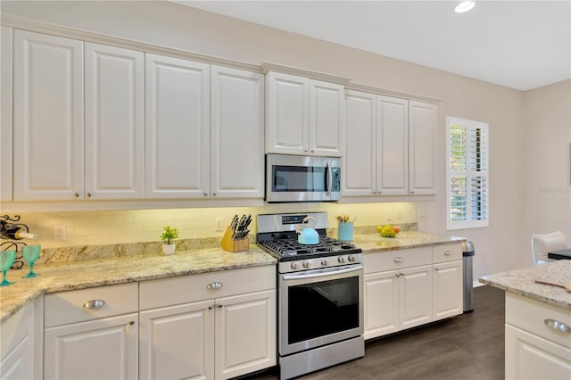 13872 Siena Loop, Lakewood Ranch, FL 34202 - kitchen with appliances with stainless steel finishes, dark wood finished floors, tasteful backsplash, white cabinets, and light stone countertops