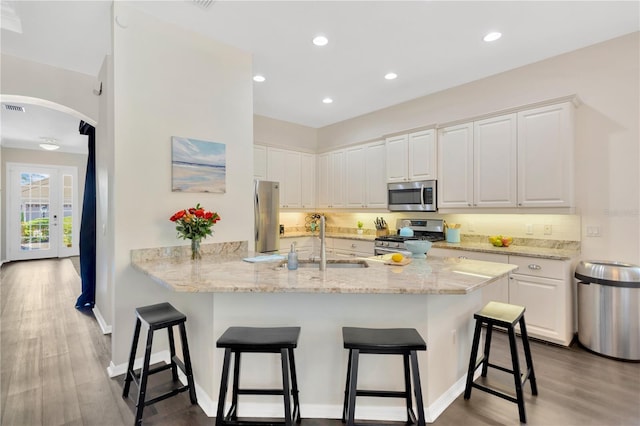 13872 Siena Loop, Lakewood Ranch, FL 34202 - kitchen featuring appliances with stainless steel finishes, a sink, arched walkways, a peninsula, and white cabinets