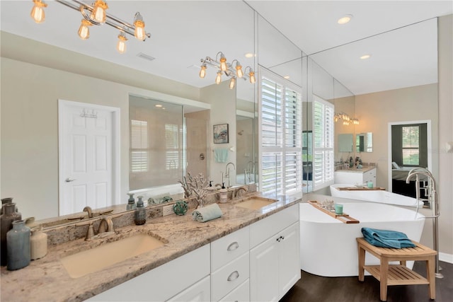 13872 Siena Loop, Lakewood Ranch, FL 34202 - bathroom with double vanity, a freestanding tub, a chandelier, wood finished floors, and a shower stall