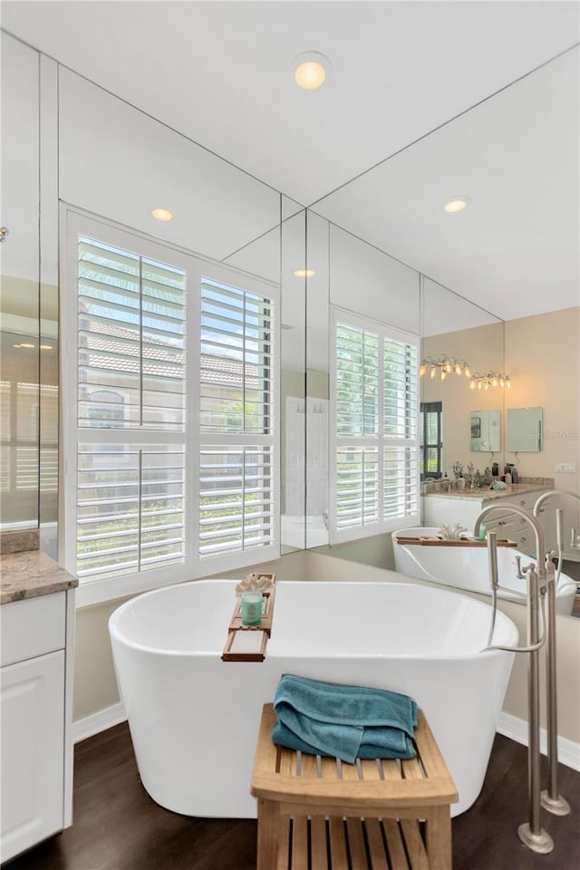 13872 Siena Loop, Lakewood Ranch, FL 34202 - bathroom featuring double vanity, wood finished floors, a soaking tub, plenty of natural light, and recessed lighting