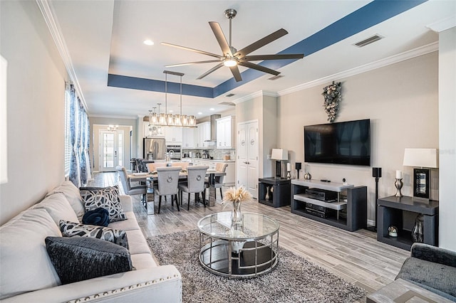 2515 63rd Ter E, Ellenton, FL 34222 - living area featuring a raised ceiling, ceiling fan, light wood finished floors, ornamental molding, and a chandelier