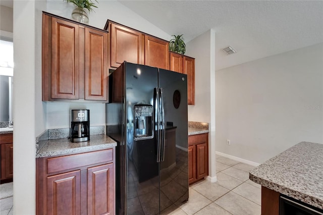 11121 Hudson Hills Ln, Riverview, FL 33579 - kitchen featuring black refrigerator with ice dispenser, light tile patterned floors, brown cabinets, and vaulted ceiling