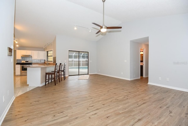 24 Lake Vista Way, Ormond Beach, FL 32174 - unfurnished living room with track lighting, light wood-style floors, a ceiling fan, high vaulted ceiling, and baseboards