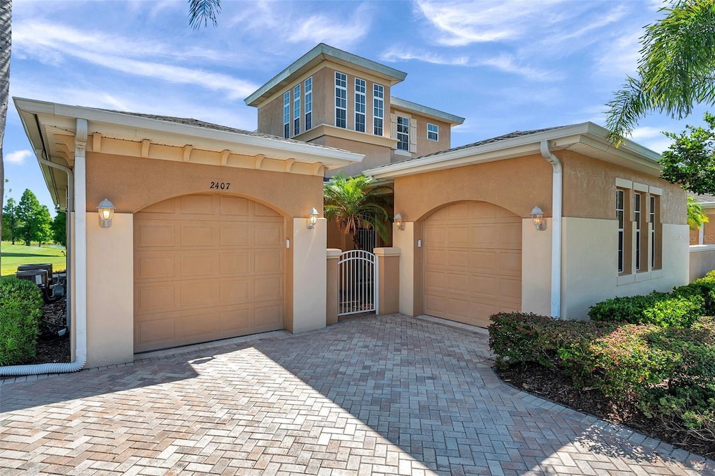 2407 Kensington Greens Dr, Sun City Center, FL 33573 - view of front of home featuring stucco siding, decorative driveway, a garage, and a gate
