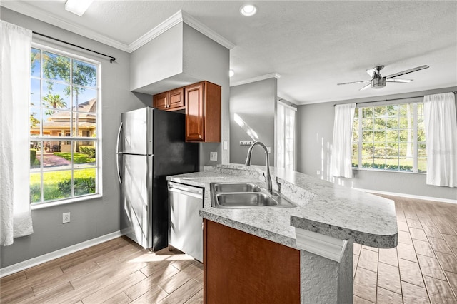 9416 Lake Chase Island Way Unit 9416, Tampa, FL 33626 - kitchen with appliances with stainless steel finishes, a sink, brown cabinetry, light wood-type flooring, and a peninsula