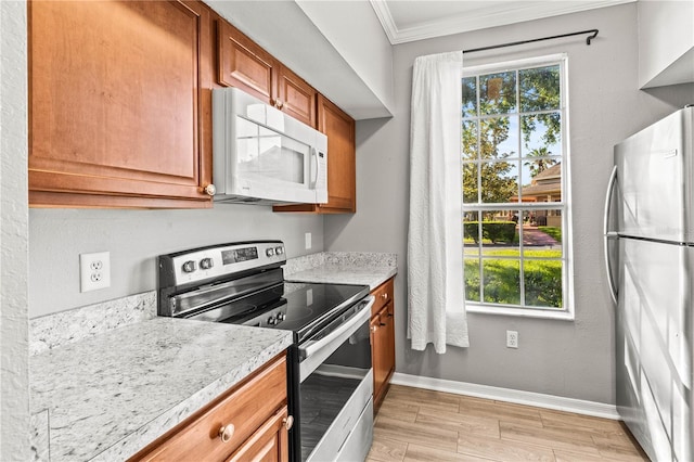 9416 Lake Chase Island Way Unit 9416, Tampa, FL 33626 - kitchen featuring stainless steel appliances, crown molding, healthy amount of natural light, baseboards, and brown cabinets