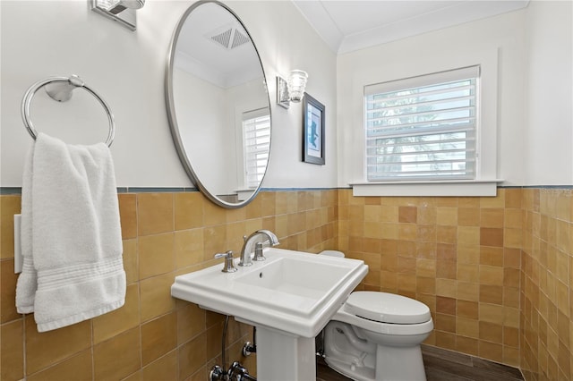 2903 Pass A Grille Way, St Pete Beach, FL 33706 - half bath featuring tile walls, plenty of natural light, toilet, and a wainscoted wall