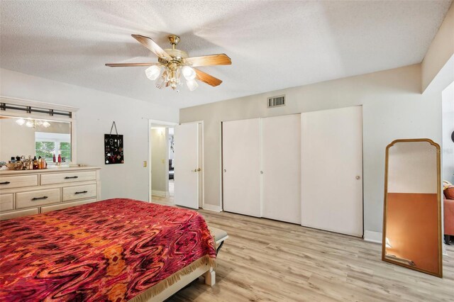 2416 World Parkway Blvd Unit 26, Clearwater, FL 33763 - bedroom with light wood-type flooring, a closet, ceiling fan, a textured ceiling, and baseboards