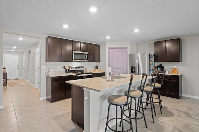 8508 Bay Dr, Spring Hill, FL 34606 - kitchen featuring appliances with stainless steel finishes, a sink, dark brown cabinetry, a breakfast bar area, and recessed lighting
