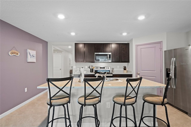 8508 Bay Dr, Spring Hill, FL 34606 - kitchen with appliances with stainless steel finishes, a breakfast bar area, dark brown cabinets, light tile patterned floors, and recessed lighting