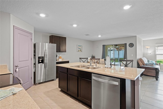 8508 Bay Dr, Spring Hill, FL 34606 - kitchen featuring stainless steel appliances, a sink, dark brown cabinets, a center island with sink, and light tile patterned floors