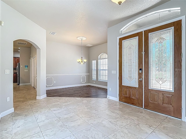 13110 Manistee Rd, Weeki Wachee, FL 34614 - foyer entrance with a chandelier, arched walkways, french doors, a textured ceiling, and baseboards