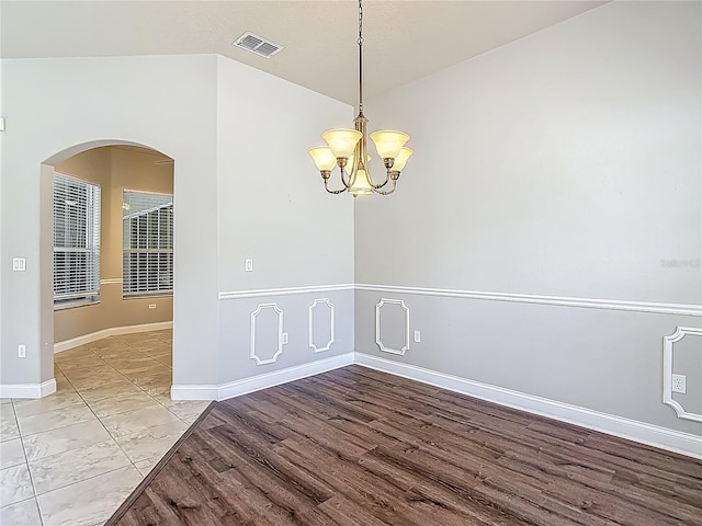 13110 Manistee Rd, Weeki Wachee, FL 34614 - unfurnished room with arched walkways, a chandelier, light wood-style flooring, and baseboards
