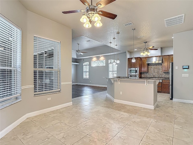 13110 Manistee Rd, Weeki Wachee, FL 34614 - kitchen with a ceiling fan, appliances with stainless steel finishes, open floor plan, light tile patterned floors, and a breakfast bar area