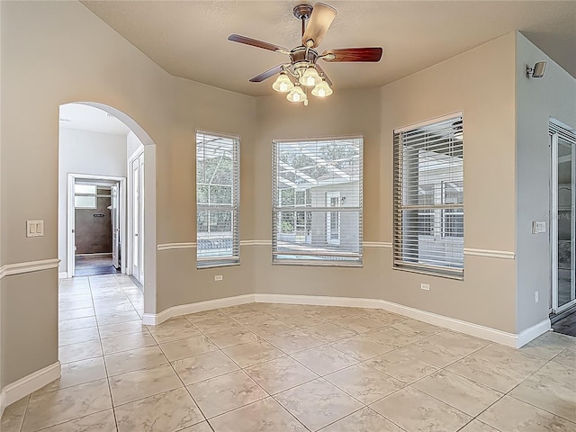 13110 Manistee Rd, Weeki Wachee, FL 34614 - unfurnished dining area featuring arched walkways, light tile patterned floors, a ceiling fan, and baseboards